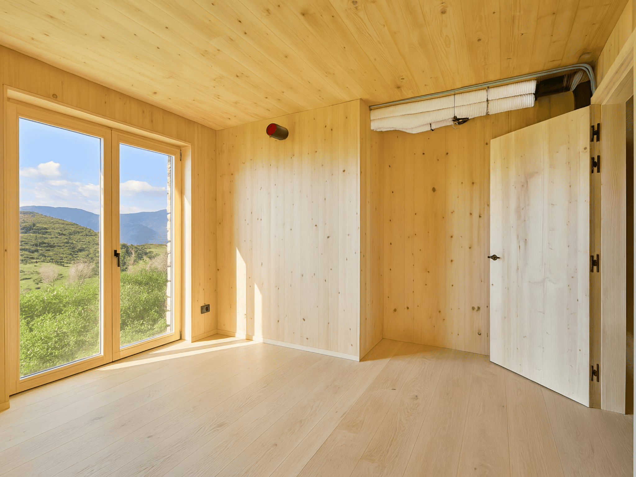 Casa sostenible de madera en Cortàs, La Cerdanya, con vistas al valle, grandes ventanales, orientación sur y diseño pasivo eficiente energéticamente.