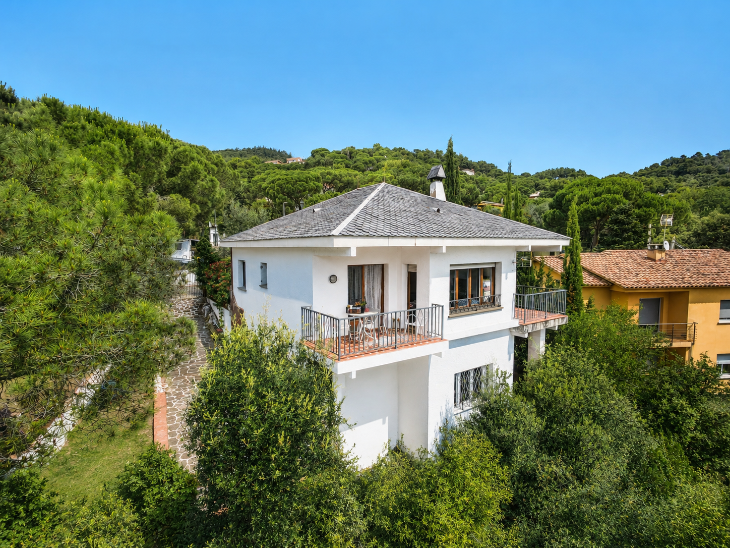 Casa unifamiliar en venta en El Serrat, L’Ametlla del Vallès, con vistas abiertas a mar y montaña, terrazas, jardín boscoso, piscina en desuso y parcela urbana anexa opcional.