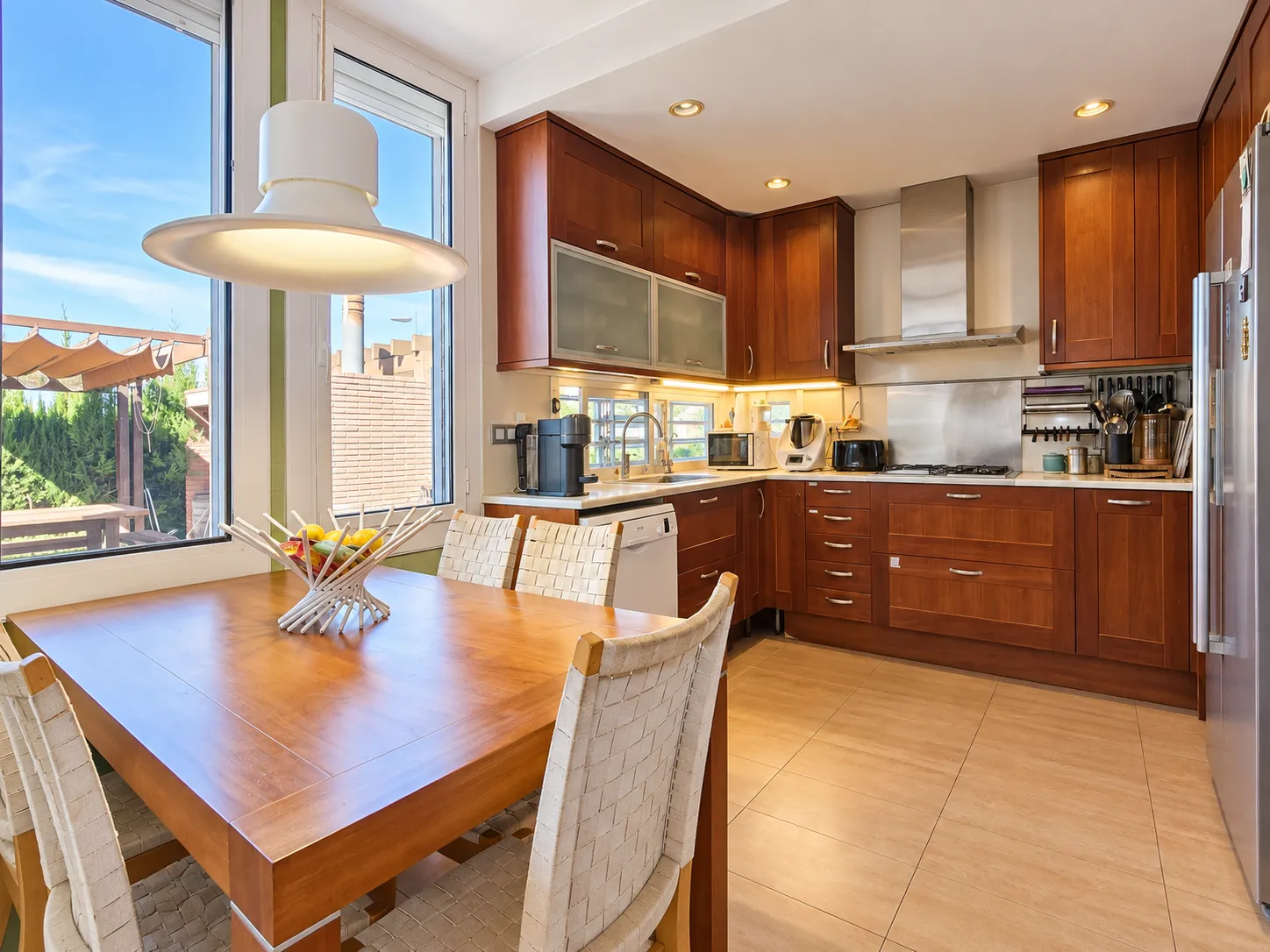 Cocina de madera de cerezo con mesa y salida al jardín