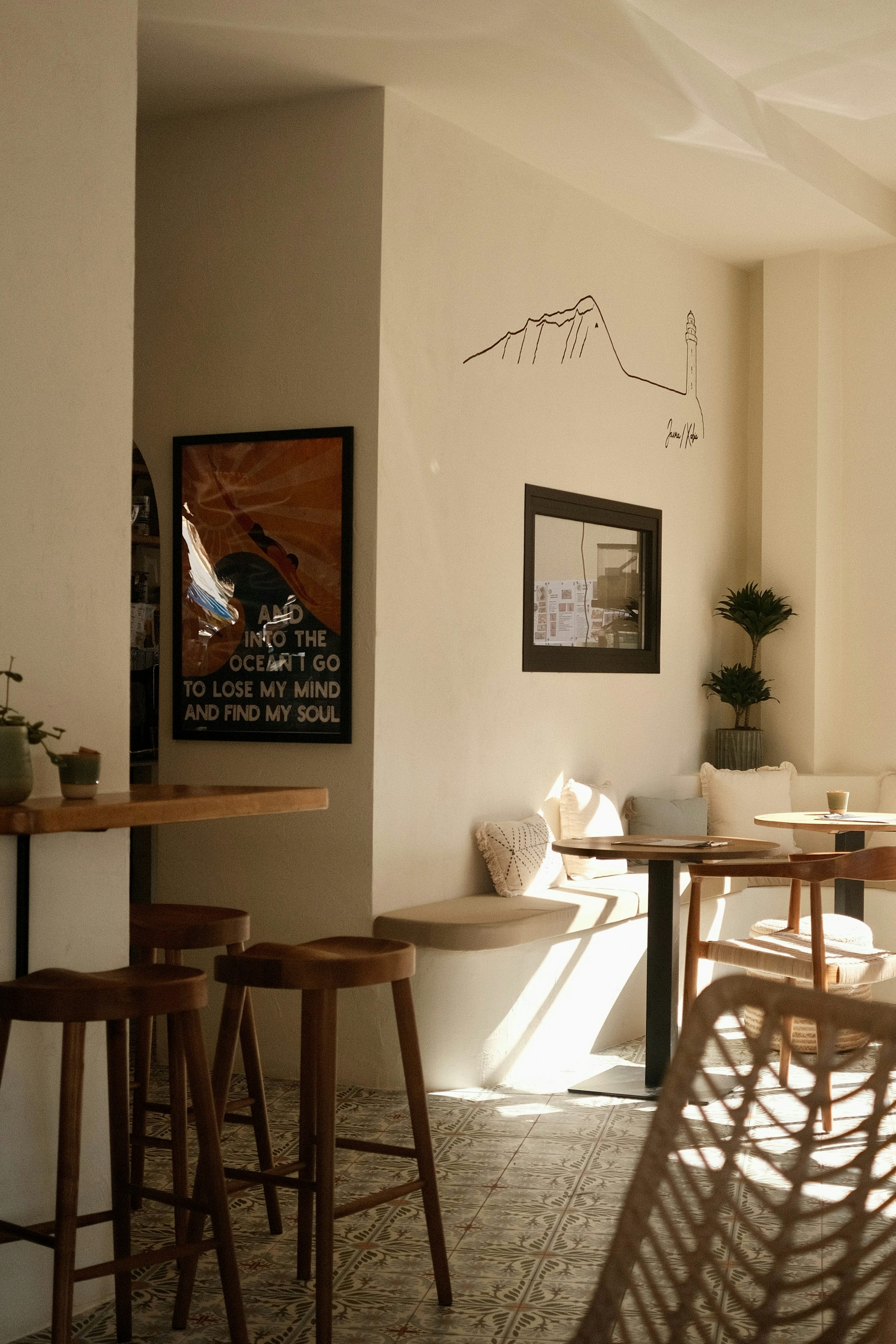 Interior de una cafetería en Jávea con luz natural, mesas de madera y paredes claras.